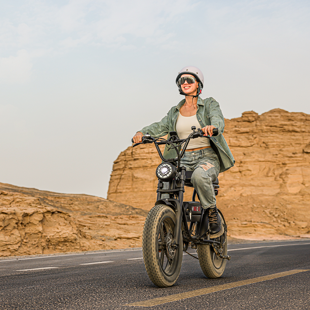 A woman rides a Windone K2 Fat Tire Electric Bike on a concrete road in the desert